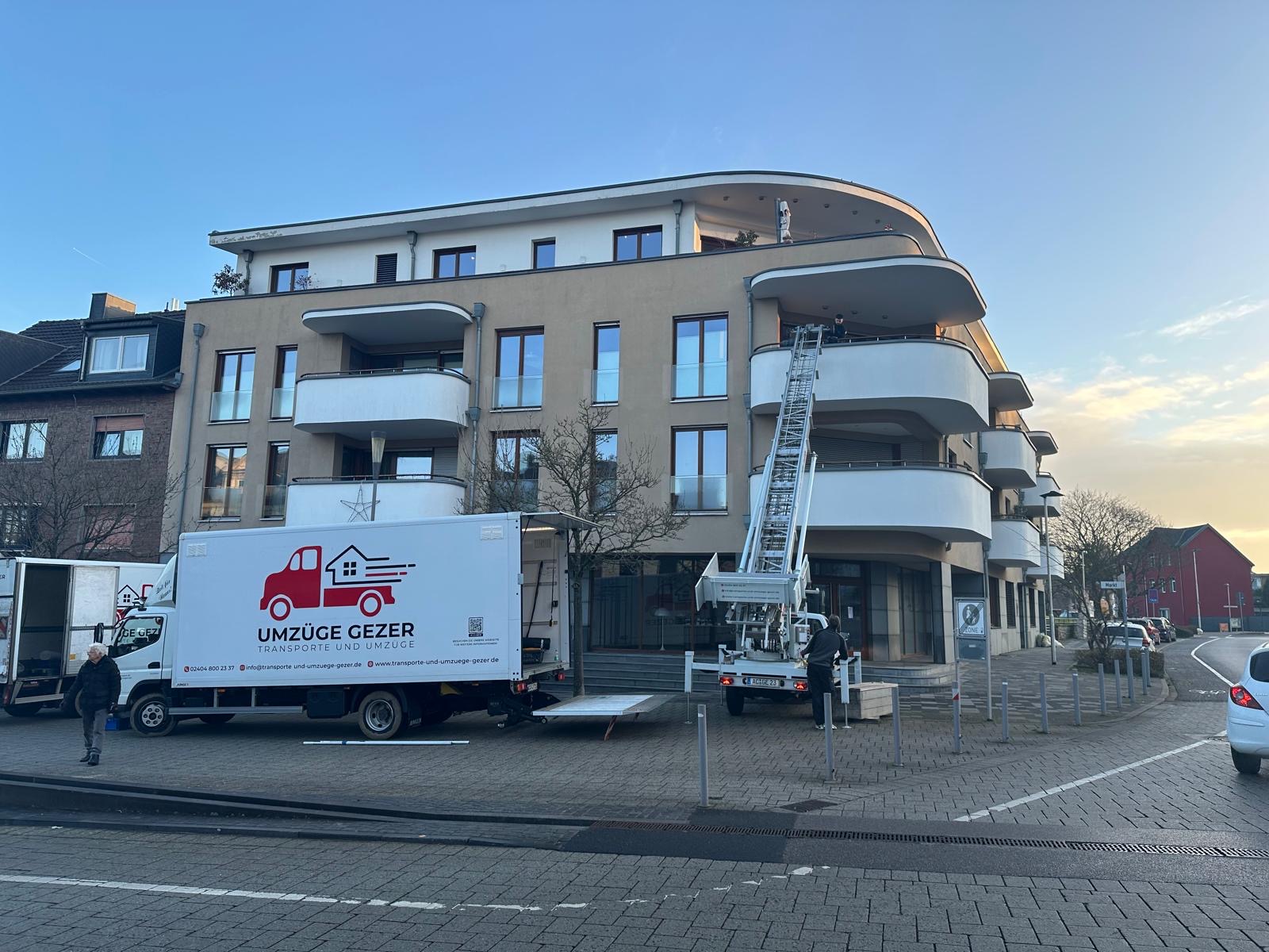 Gezer Umzüge im Einsatz mit LKW und Möbellift vor modernem Gebäude